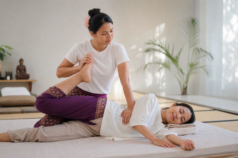 Massagista realizando alongamento de massagem tailandesa